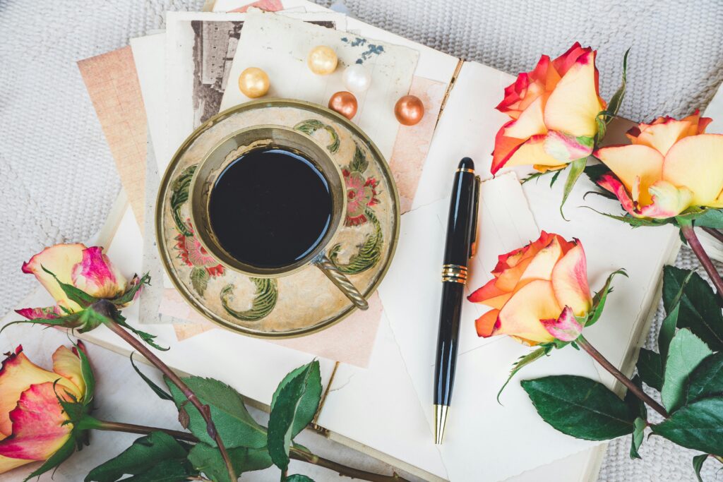 pexels-photo-10874310-10874310 A beautiful flat lay of a coffee cup, roses, and pen on a cozy blanket setting.